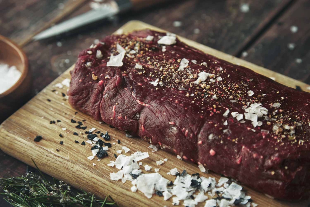 close-up-focused-piece-meat-salted-peppered-wooden-board-vintage-table-spices